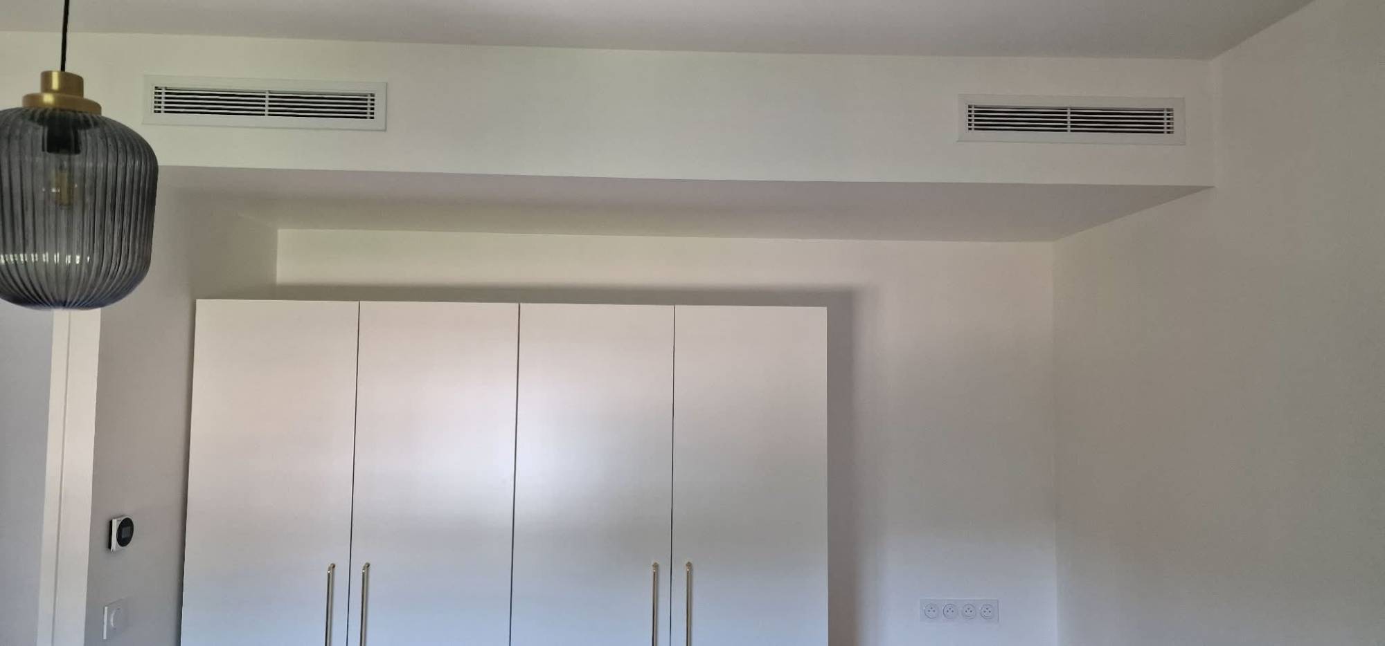 Grilles de soufflage intégrées dans un coffrage au-dessus d'un placard